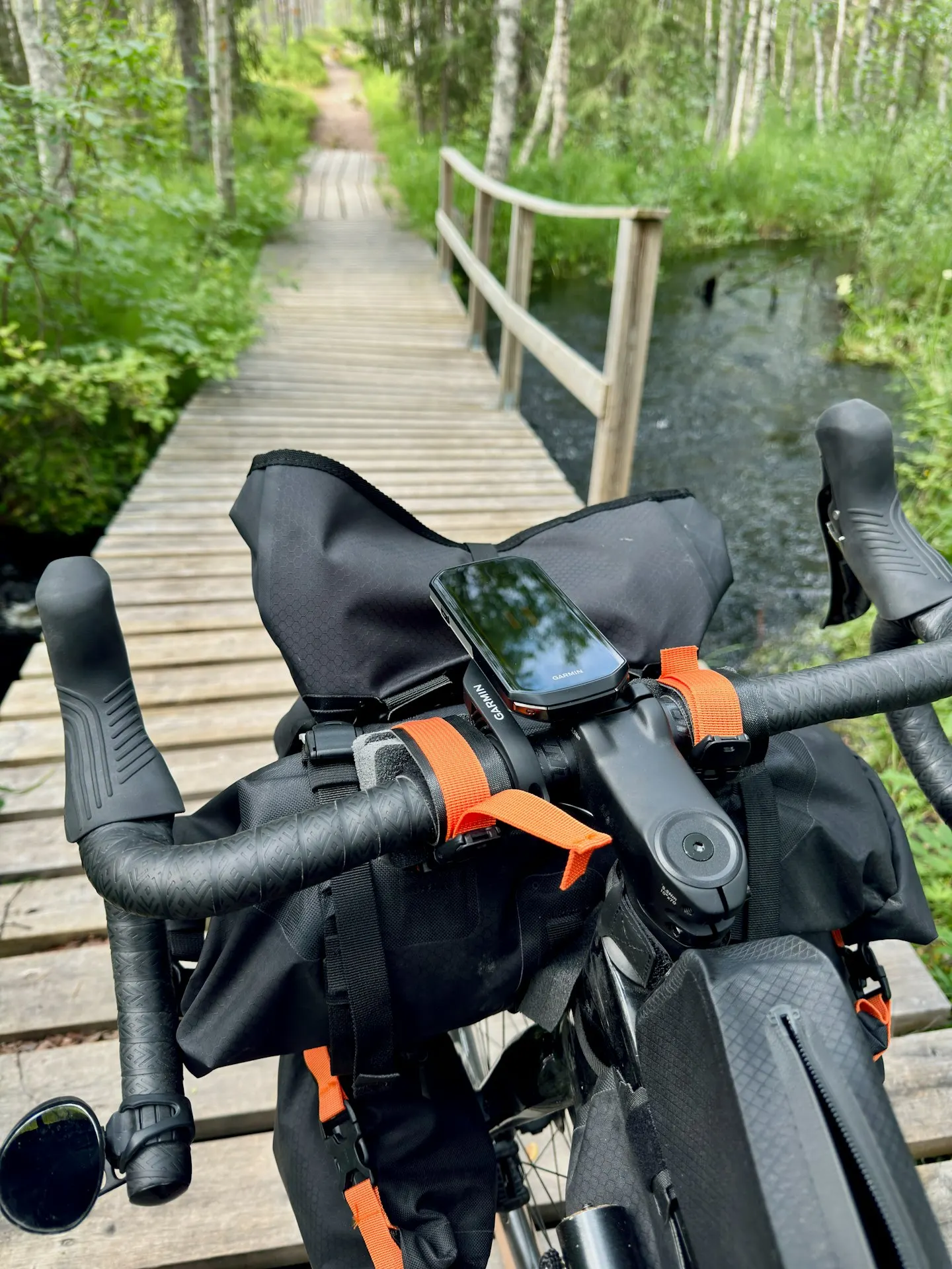 Vélo de bikepacking avec sacoche de cintre et compteur GPS, sur une passerelle en bois