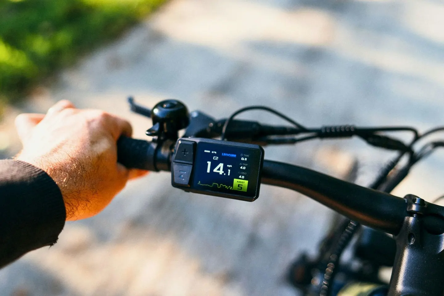 Main sur le cintre d'un vélo électrique avec l'écran d'assistance d'origine